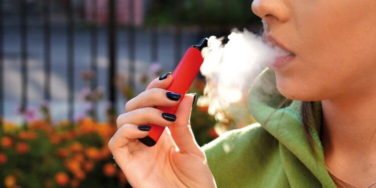 beautiful women smoke electronic cigarette in street